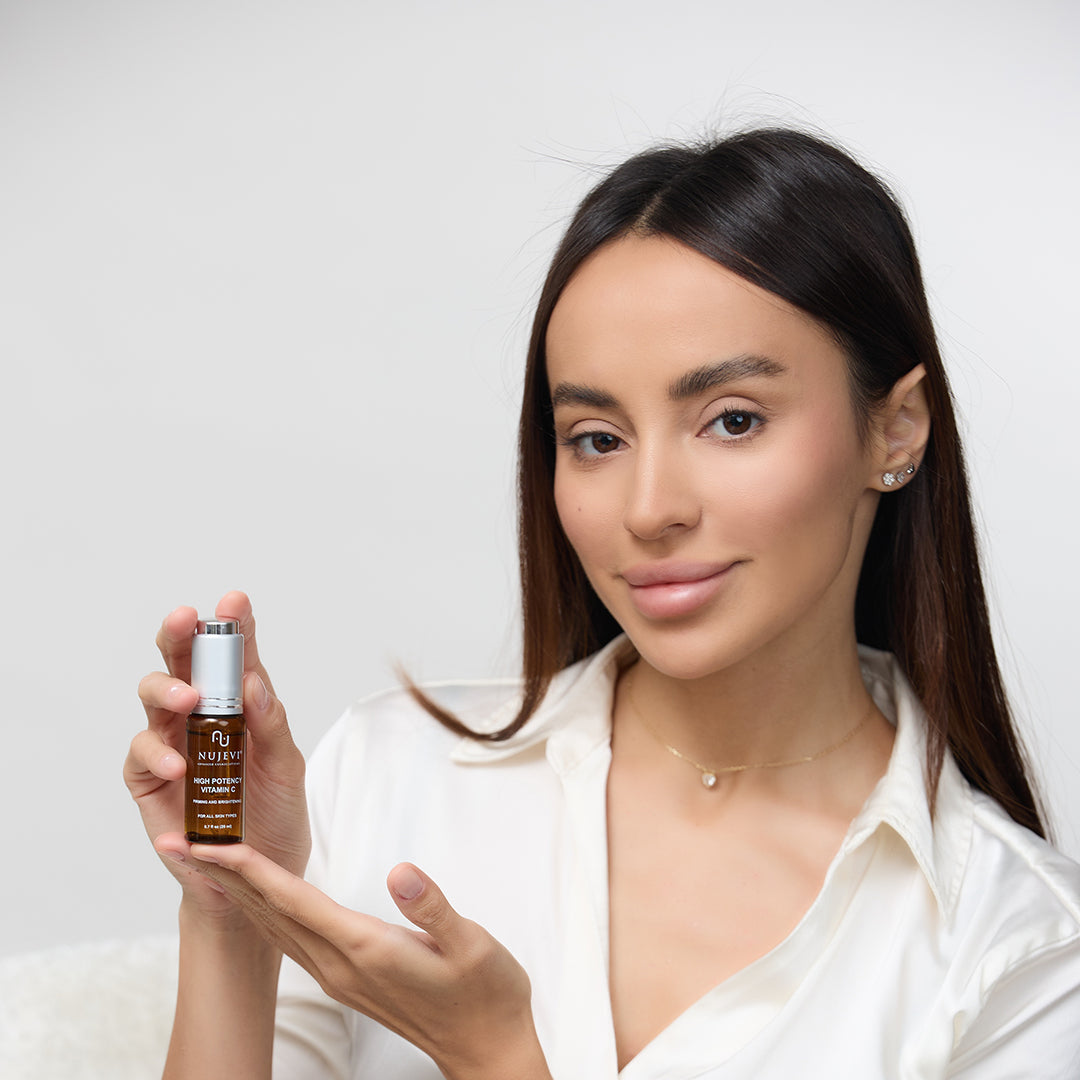 Young woman holding brown dropper bottle that reads "High Potency Vitamin C" in her hands